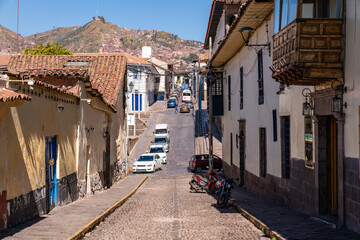Blick eine steile, gepflasterte Straße in Cusco hinab, gesäumt von kolonialen Gebäuden