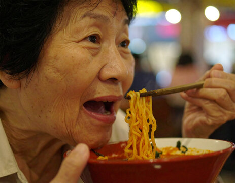 senior woman eating noodles