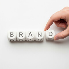 wooden cubes forming BRAND with human hand placing final block marketing concept