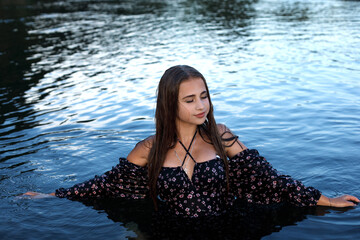 Young girl with wet hair in water at sunset