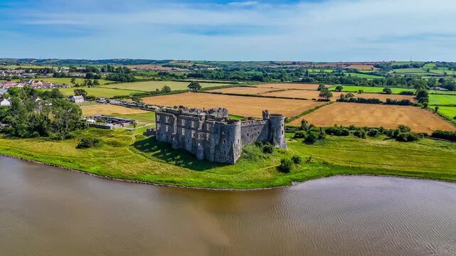 A receding aerial view towards the Castle ruins at Carew, South Wales in summertime