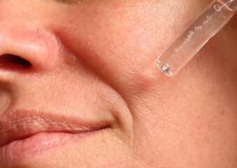 Obraz premium Closeup of woman applying facial hydration serum on her face. Woman in her 40s doing her beauty routine. Skin care routine.