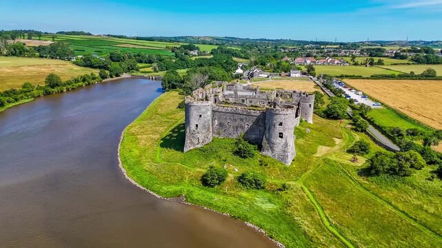 A full semicircle rotating aerial view around the Castle ruins at Carew, South Wales in summertime