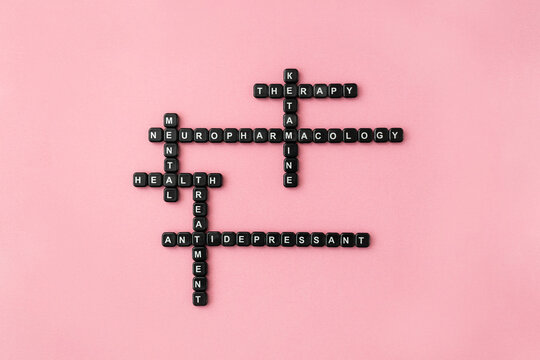Words neuropharmacology, ketamine therapy and antidepressant made up of black plastic letter blocks on pink background. Mental health treatment crossword. Selective focus
