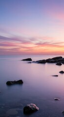 Naklejka premium Serene Ocean Sunset with Purple and Pink Sky and Rocks