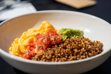  Buckwheat, avocado, scrambled eggs, and diced tomatoes create a vibrant and nutritious meal in...