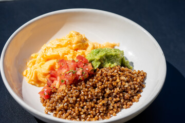  Buckwheat, avocado, scrambled eggs, and diced tomatoes create a vibrant and nutritious meal in...