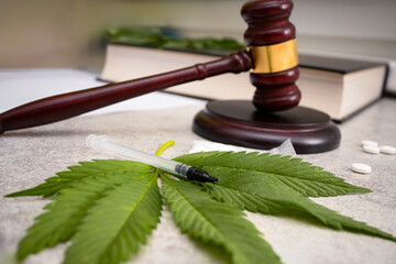 Gavel, syringe, pills and marijuana leaf illustrating the legal aspects of medical cannabis