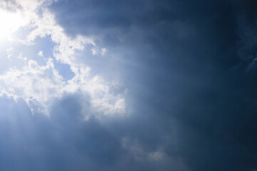Dramatic sky with sunlight breaking through dark clouds creating a moody atmosphere