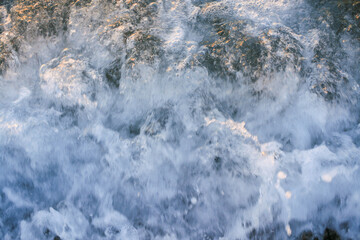 Dynamic waves crashing against rocky shore creating a mesmerizing natural water texture