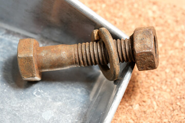 Rusty bolt and washer resting on a metal tray in a workshop setting