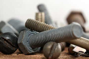 Rusty bolts and screws scattered on a wooden surface in a workshop
