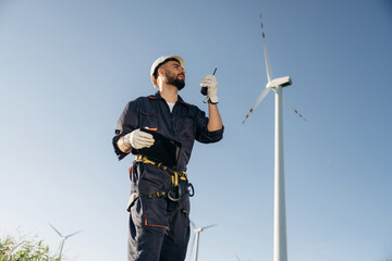 Naklejka premium Giving orders by using walkie talkie. Engineer in field checking on wind turbine production