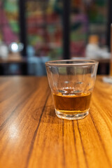 A glass of amber drink on a wooden table