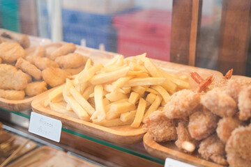 fried snacks and french fries in trays at a food stall.
