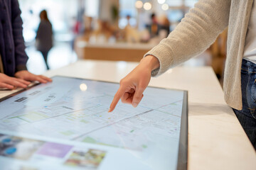 ショッピングモールのタッチパネル案内端末を操作する女性の手元