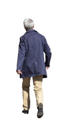 Fototapeta premium Homme aux cheveux gris vu de dos, qui marche en extérieur, portant un manteau bleu marine et un pantalon beige par une journée ensoleillée, tient un livre dans sa main droite