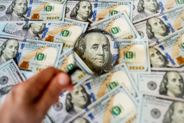 a lot of money banknotes of one hundred 100 American dollars lie on the table in a chaotic order,...