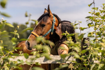 Young woman bonding with a Barb Arabian horse outdoors in summer
