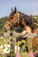Young woman bonding with a Barb Arabian horse outdoors in summer