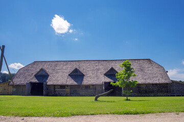 Ancient peasant Lithuanian house with a wooden roof on a blue sky background