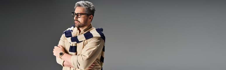 Handsome man in stylish outfit with glasses poses elegantly in studio setting