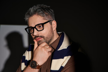 Man in glasses poses thoughtfully in a modern studio during a fashion shoot