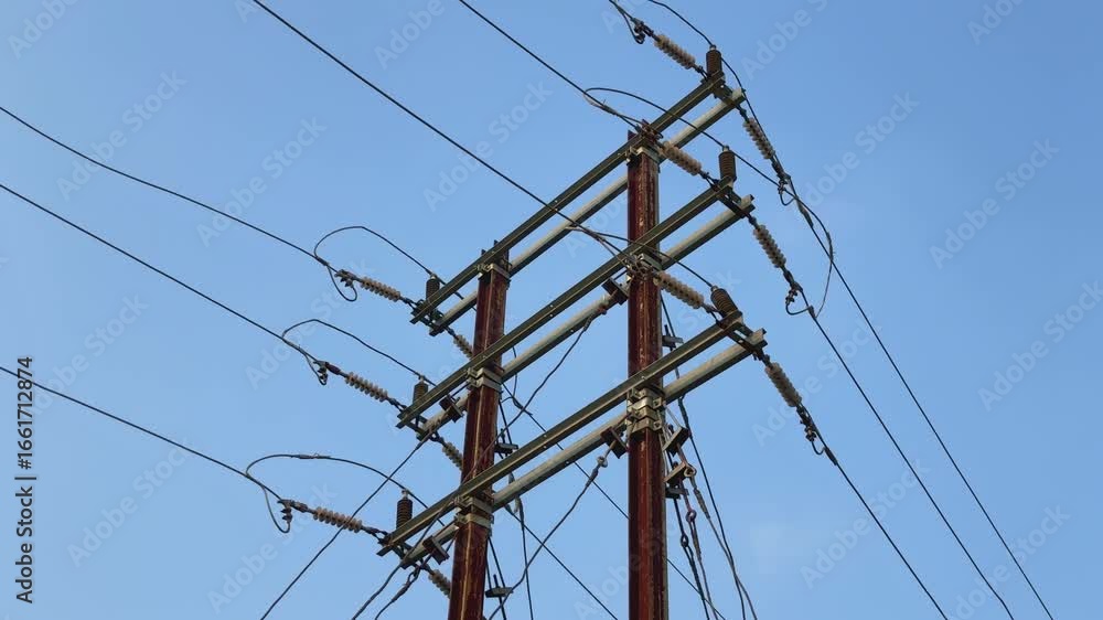 Poster static shot of a power transmission tower against a clear blue sky. the tower is constructed from me