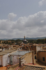 Panoramic view of Tortosa with its church dome, surrounding rooftops, and distant mountains beneath cloudy skies.