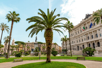 Palm tree in Piazza Cavour square in Rome, Italy, with Palace of Justice and historic monument in background