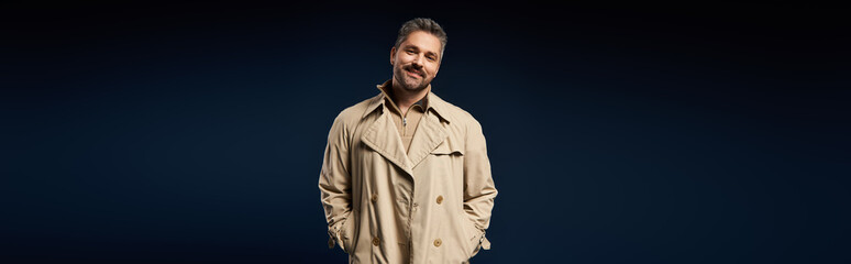 Handsome man in stylish trench coat poses confidently in a trendy studio setting