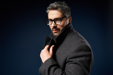 Elegant man showcases stylish glasses and sophisticated outfit in studio setting