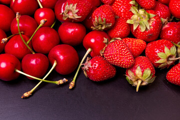 Strawberries and cherries on a black background