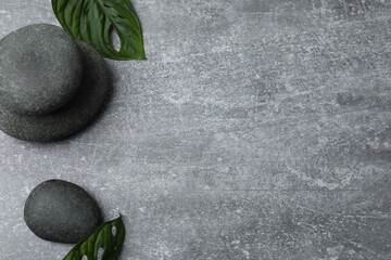 Top view of spa stones set for massage with green leaves on concrete background with copy space....