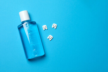 Mouthwash bottle for oral hygiene on blue background. Rinsing mouth with liquids helps against bad breath, cavities and plaques. Dental care product. Copy space.