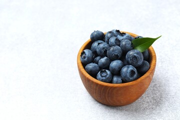 Ripe blueberries in a wooden bowl. Healthy and dietary nutrition concept. Top view.