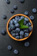 Delicious fresh blueberries in a bowl on a gray table, close-up