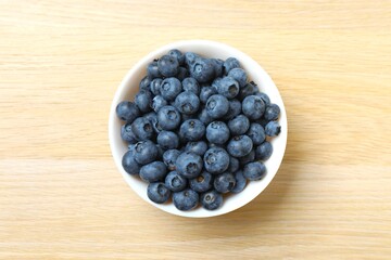 Bowl with fresh blueberries on wooden background. Top view
