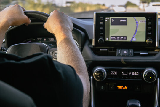 Driver holding steering wheel with GPS navigation screen