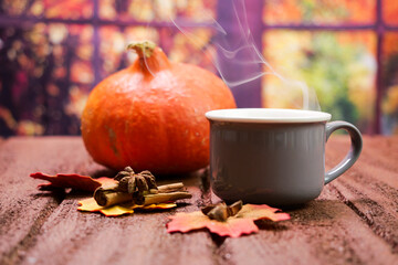Bevanda calda autunnale, tazza fumante sul tavolo, foglie secche, zucca, cannella a anice