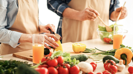Homemade food. Happy couple at home preparing together yummy dinner for family lunch, enjoying cooking process, caring for health, eating fresh vegetable salad, cropped, close up, free space