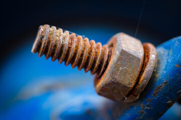 Close-up of a rusty tractor bolt with soft blur and vibrant blue tones, ideal for industrial-themed backgrounds and creative design.