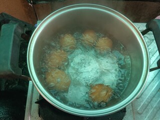 Egg boiling in hot water. Cooking process in metal pot. Gas stove in kitchen. Bubbling water with steam. Preparing hard boiled egg. Closeup of food in pan. Domestic breakfast preparation.