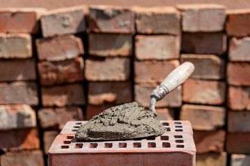 Cement mix or mortar. Cement powder and trowel on red brick at construction site, closeup