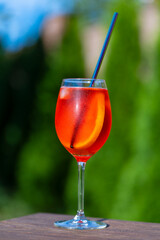 Aperol spritz cocktail in wine glass on a nature background. Classic italian aperitif aperol spritz cocktail with slice of orange. Closeup. Summer refreshing drink with sunlight