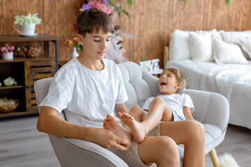 Happy positive children, tickling on the feet, having fun together, boy brothers having wonderful...