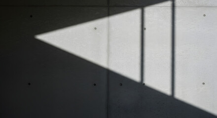 Abstract interplay of light and shadow creates geometric patterns on a textured concrete wall, highlighting minimalist design and architectural forms. The mood is serene and contemplative.