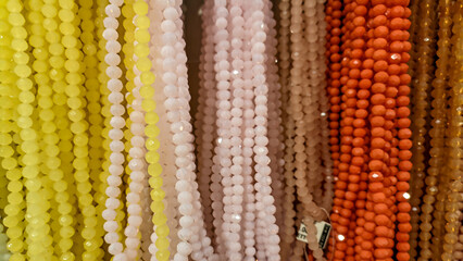 Rows of colorful pearl beads are displayed in a row. The beads are of various colors and are...