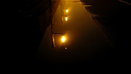 Mysterious Glow Reflected in Dark Water Under Soft Orange Lights
