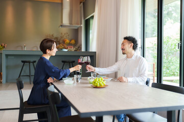 モダンなリビングダイニングで赤ワインを飲む夫婦